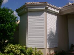 white roll down hurricane shutters on tan house