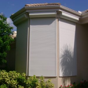 white roll down hurricane shutters on tan house