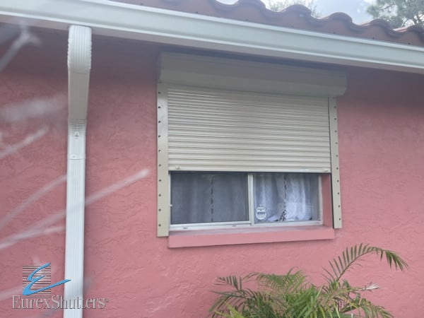 Beige rolling storm shutters on a pink home in Lehigh Acres FL. 