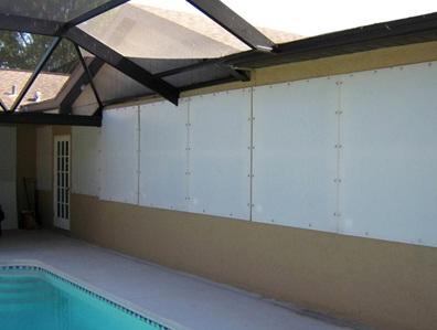 White hurricane fabric panels installed on a tan home's patio near a blue pool