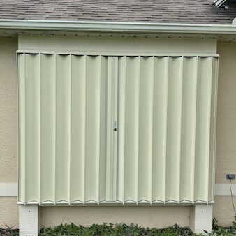 Ivory accordion shutters on a tan home in Southwest Florida
