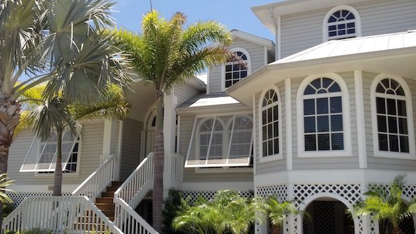 White Bermuda shutters on a grey home