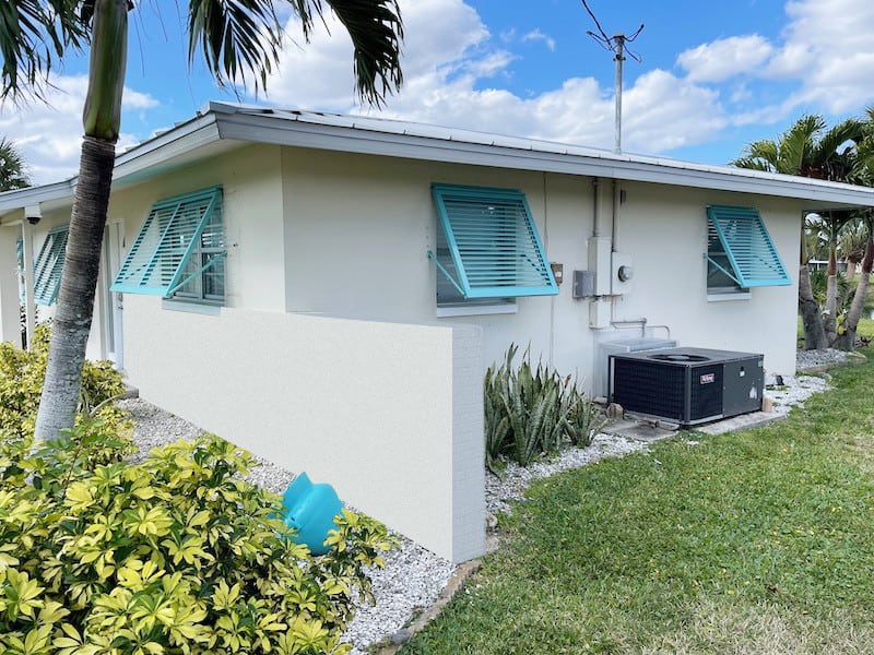 Custom Eurex Shutters PTX Bahama Shutters in custom tiffany blue color shown on the side of a home in Lehigh Acres FL