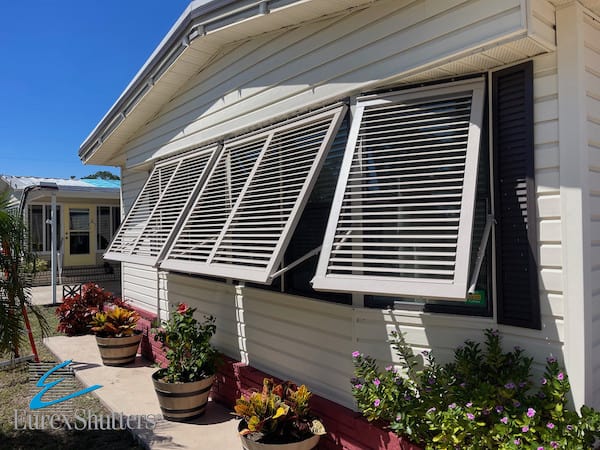 Beige Bahama hurricane shutters on the front window of a beige modular home in North Fort Myers