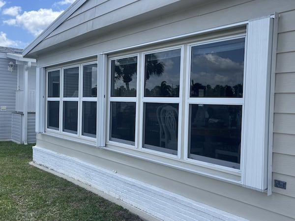 White Accordion Shutters in the open position over a row of 6 windows on a home in South Naples FL.