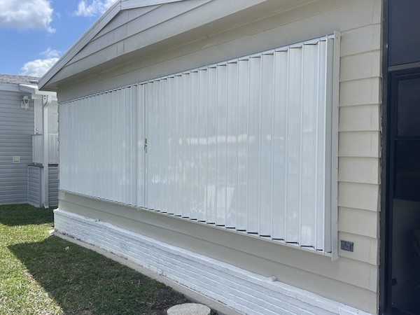 White Accordion Shutters closed over a row of 6 windows on a home in South Naples FL.