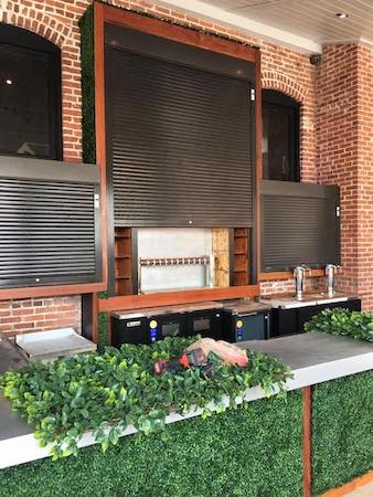 Commercial rolling shutters installed over a bar for security reasons.