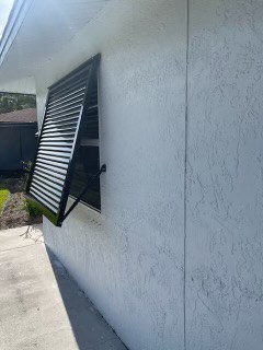 Side view of a newly installed custom, black Eurex Shutters Bahama Hurricane Shutter on a home in Lehigh Acres