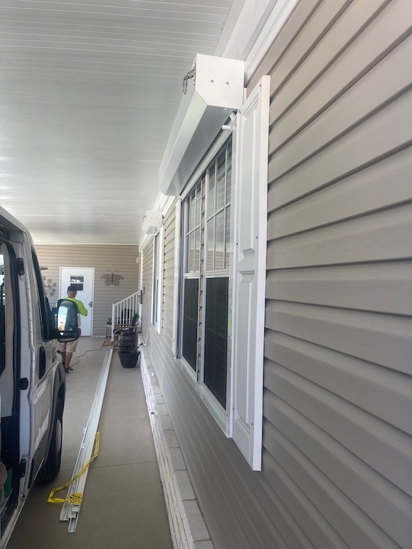 A side profile image showing white Eurex Shutters Rolling Hurricane Shutters installed on multiple windows of a beige manufactured home in South Fort Myers FL