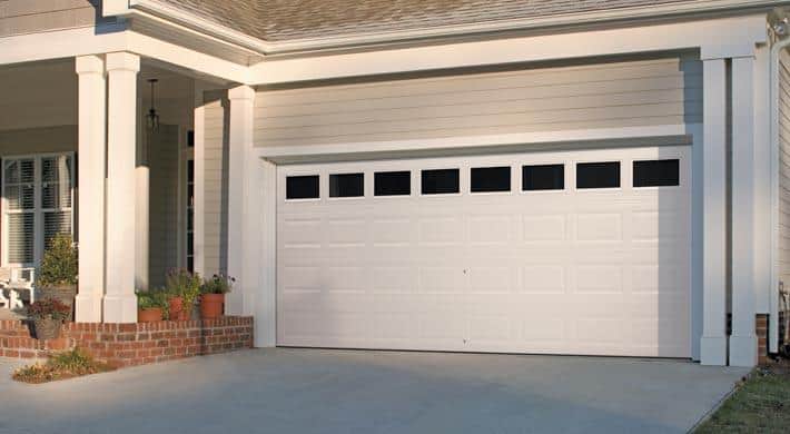 White, double hurricane garage door with 8 impact windows on an beige colored home