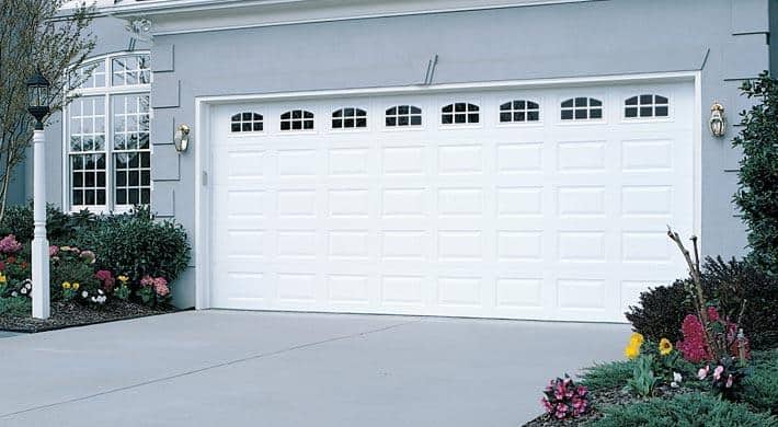 White, double hurricane garage door with impact windows on a gray home