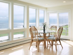 Awning windows, a popular type of impact window in Florida, is shown in a dining room of a home with a water view through the windows