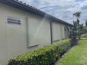 Accordion shutters shown on multiple windows of a home in Fort Myers Florida.