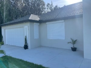 White rolling shutters shown on multiple windows of a home in Lehigh Acres Florida.