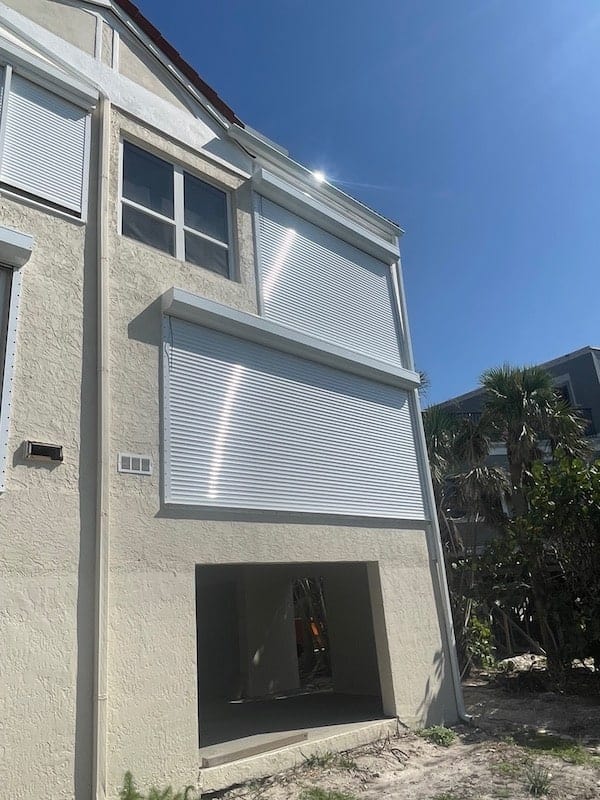 White, hvhz approved roll shutters shown closed over multiple windows on a home in Sanibel FL