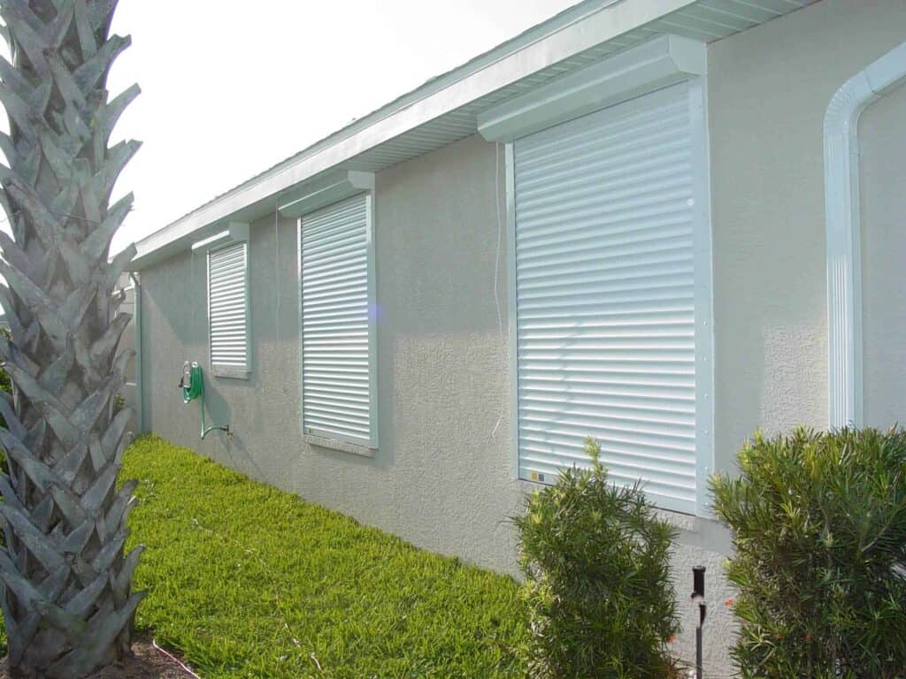 White roll shutters shown closed over multiple windows on a home in Gulf Coast Florida