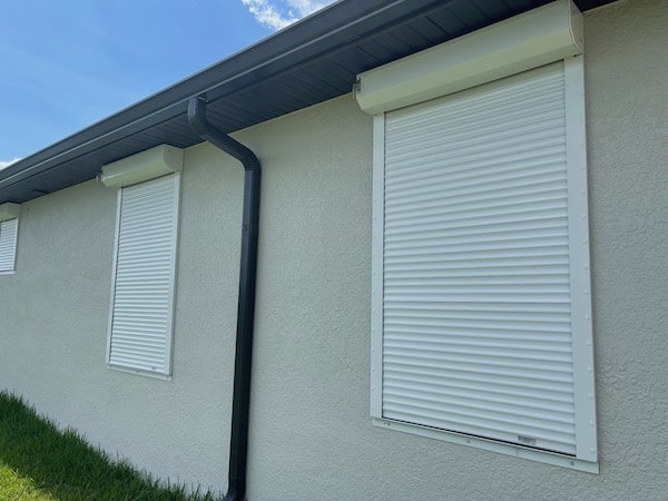 White roll shutters shown in the closed position on two windows on a home in Southwest Florida