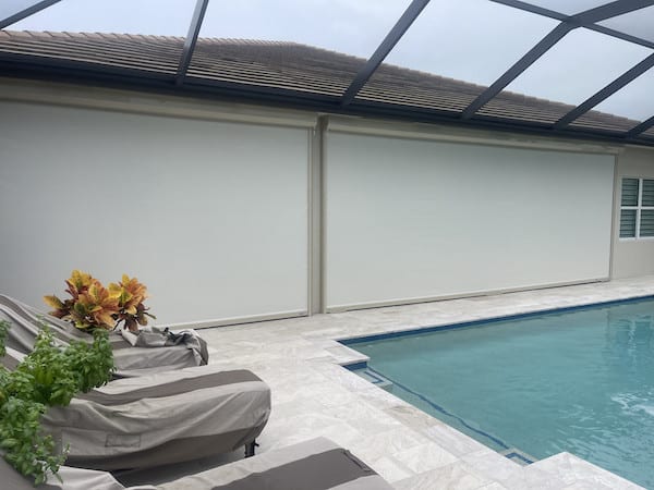 Two white/tan hurricane screens with beige housing boxes installed on a home in Bonita Springs Florida (Florida Gulf Coast).