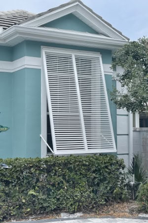 A single, white, full-view, Bahama shutter installed on the front window. In Englewood Florida.