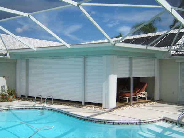 Roll down shutters with the housing box and tracks hidden from the exterior view of the house. Shown in the partially closed position, where it is possible to see that roll down shutters exist, but the housing boxes are hidden.