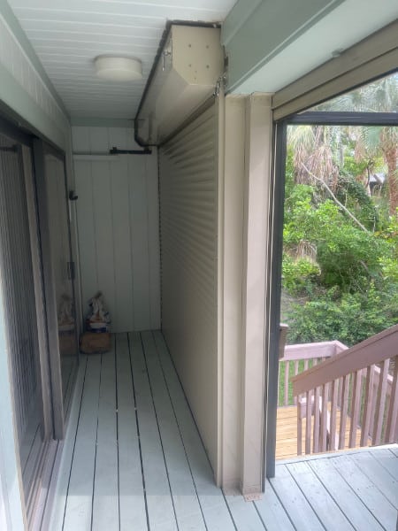 Beige roll-down shutters shown in the fully closed position on the back porch of a home in Sanibel Florida. 
