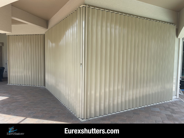 Beige accordion shutters shown closed on the patio of a beige condo unit in Fort Myers Florida
