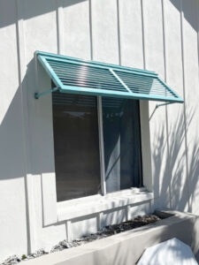 Half Bahama shutter in a custom blue color installed on a window of a home.