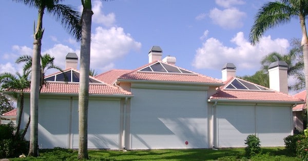 White roll shutters covering the doors and windows on the front of a tan home in Florida.