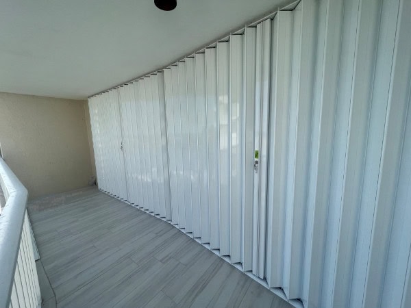 A wide width span of white colored accordion shutters shown closed over the patio doors on a condo in Marco Island Florida.