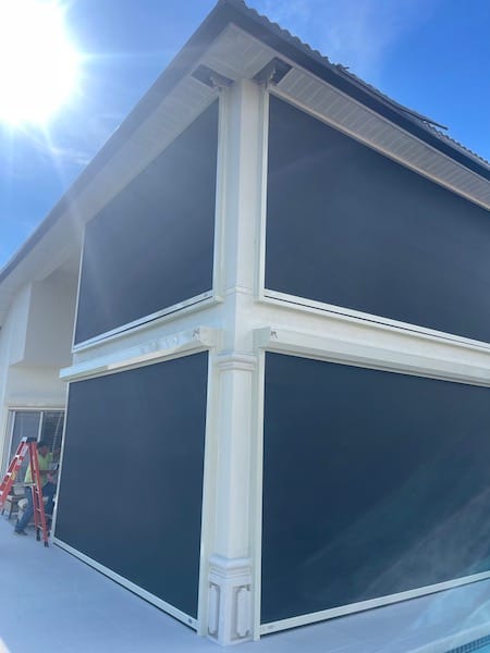 Black hurricane screens with ivory tracks being installed on the first and second floor balconies of a canal home in Cape Coral Florida by Eurex Shutters