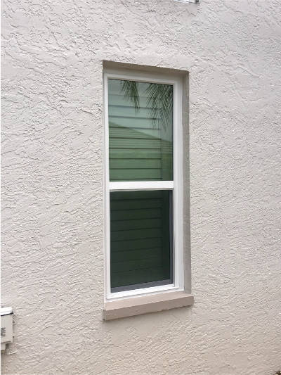 White, custom single-hung impact window installed on a beige home in Bonita Springs