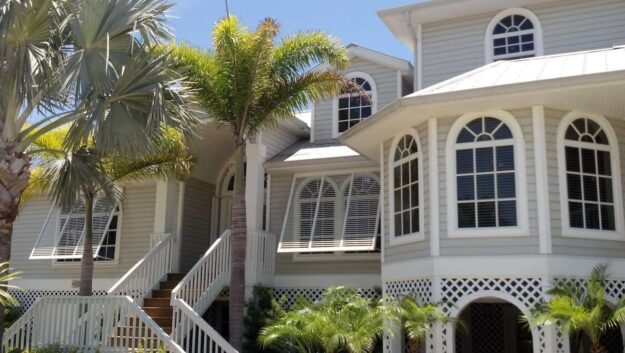 Hurricane shutters on a home in Florida with palm trees.