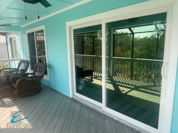 White vinyl impact windows and impact sliding glass door on a blue home