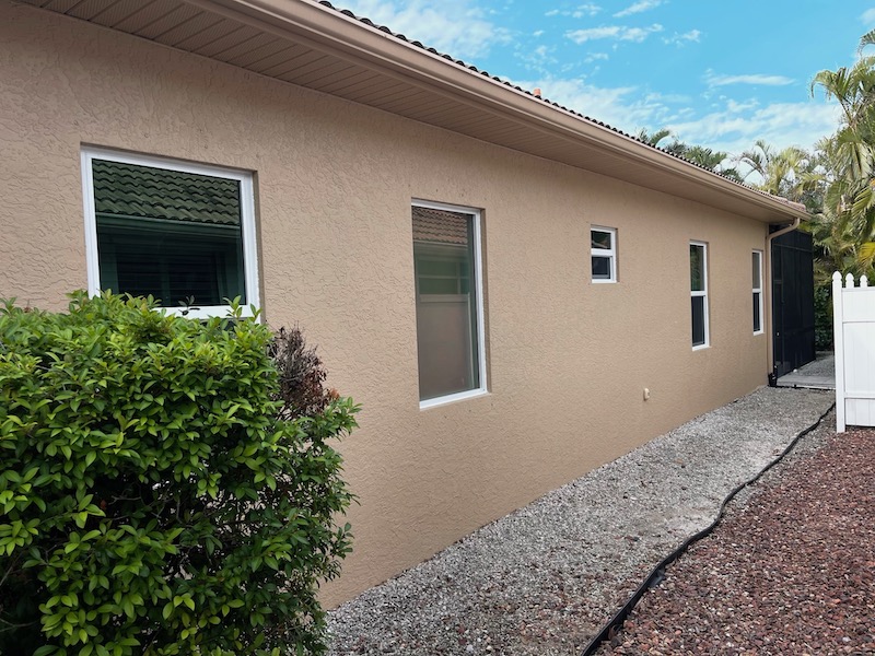 Image of a Naples, Florida home featuring newly installed white vinyl impact windows by Eurex Shutters, emphasizing durability and style.